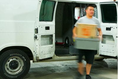 Courier driver carrying a library bin from a white van